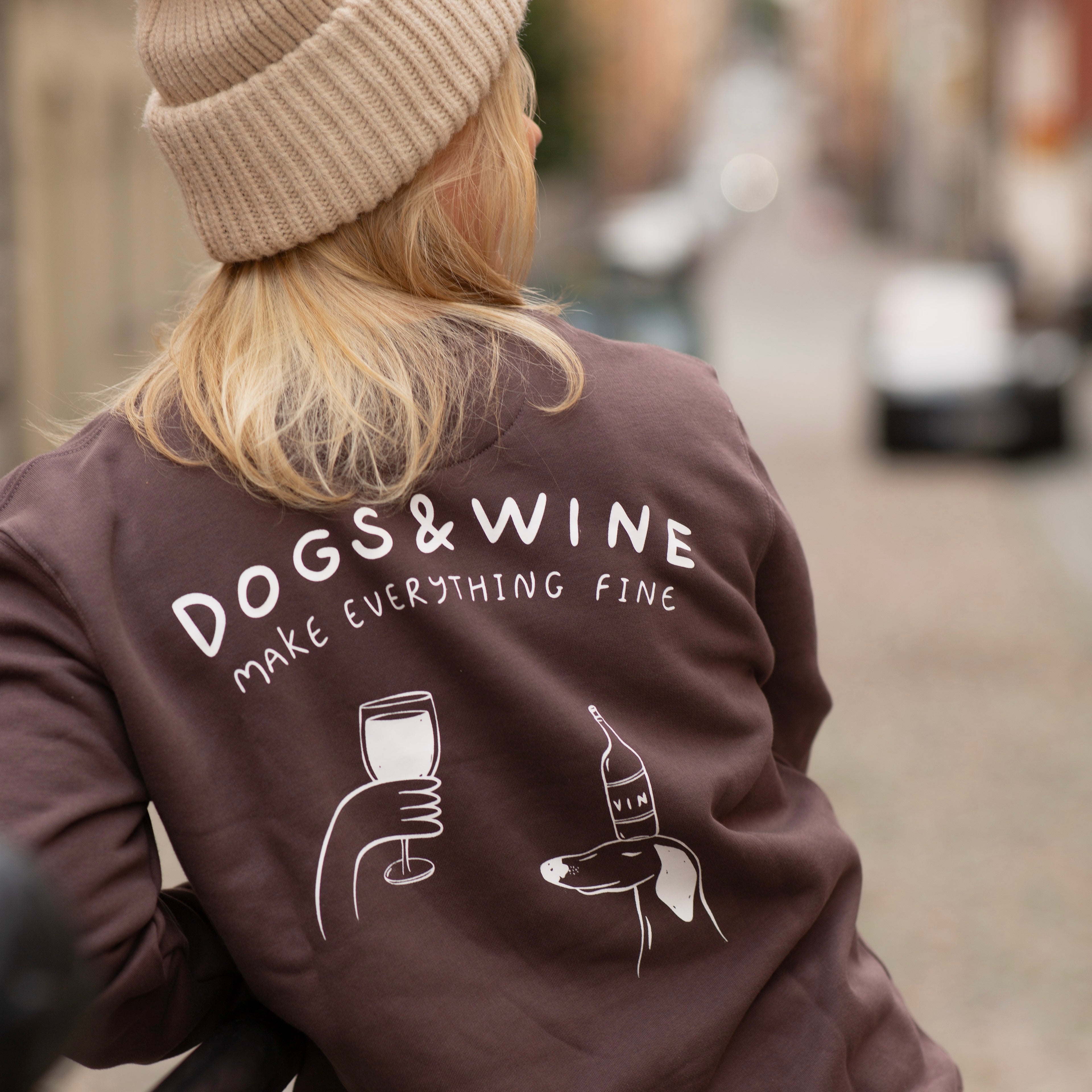Person wearing a brown jacket with 'DOGS & WINE MAKE EVERYTHING FINE' text and graphics.